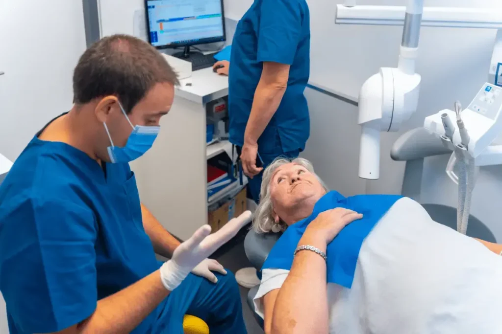 Dentist explaining procedure to patient in chair.